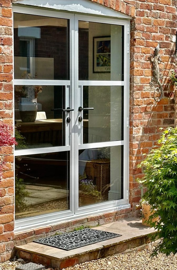 white heritage doors fitted within a curved brickwork opening.