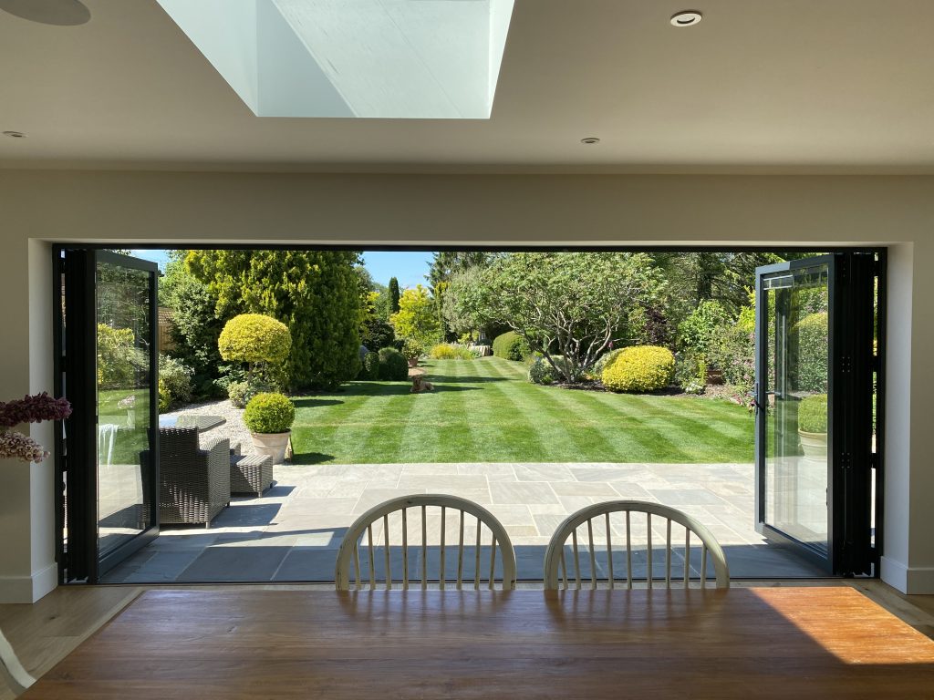 alunet bifold doors fully open with fresh cut lawn and patio view