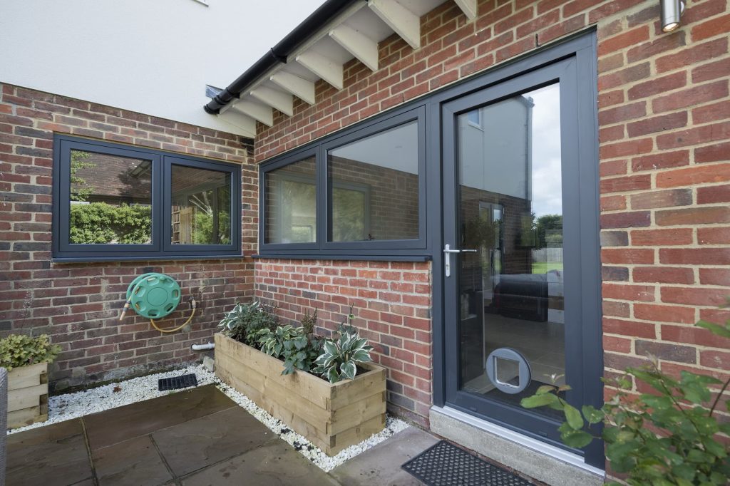 Residence collection door in a grey colour with matching grey windows at the back of a bungalow
